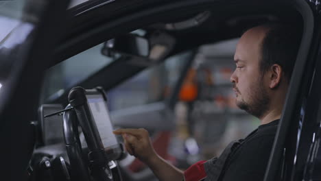 Mechanic-Uses-a-Tablet-Computer-with-an-Augmented-Reality-Diagnostics-Software.-Specialist-Inspecting-the-Car-in-Order-to-Find-Broken-Components-Inside.-male-uses-laptop-for-diagnostics-vehicle